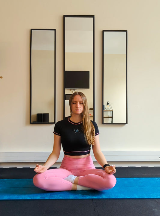 A girl doing yoga wearing pink and black activewear